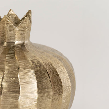 Closeup of gold pomegranate sculpture highlighting crown detail and hammered metal texture in elegant finish