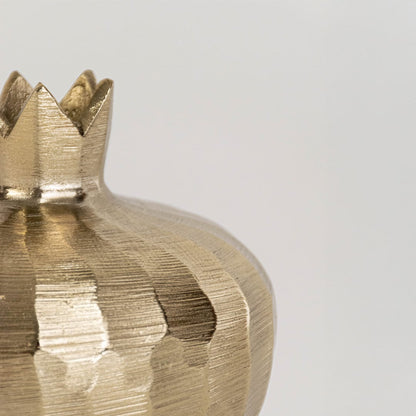 Closeup view of the gold pomegranate decor showing its hammered texture and handcrafted crown top