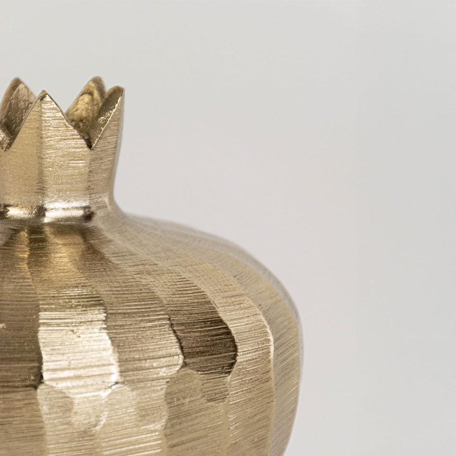 Closeup view of the gold pomegranate decor showing its hammered texture and handcrafted crown top