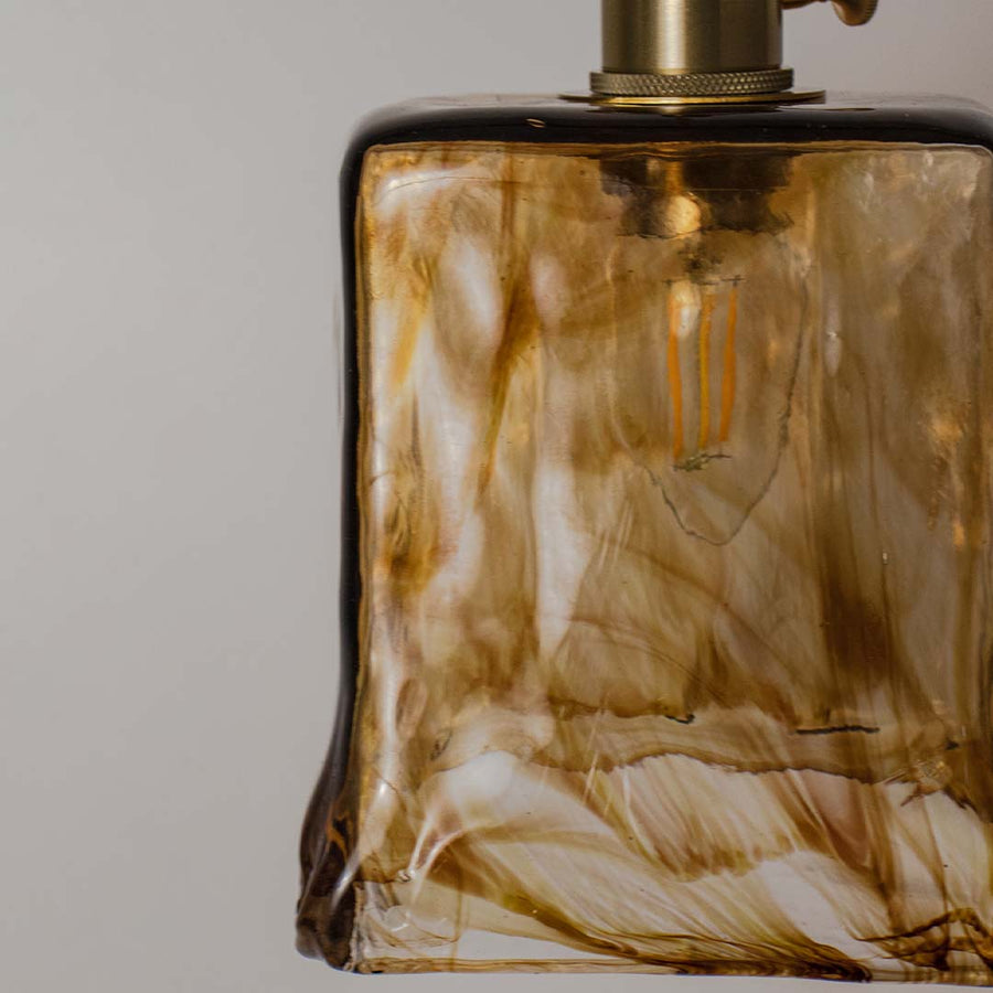 Closeup of amber textured glass pendant light showcasing intricate marbled patterns and craftsmanship.