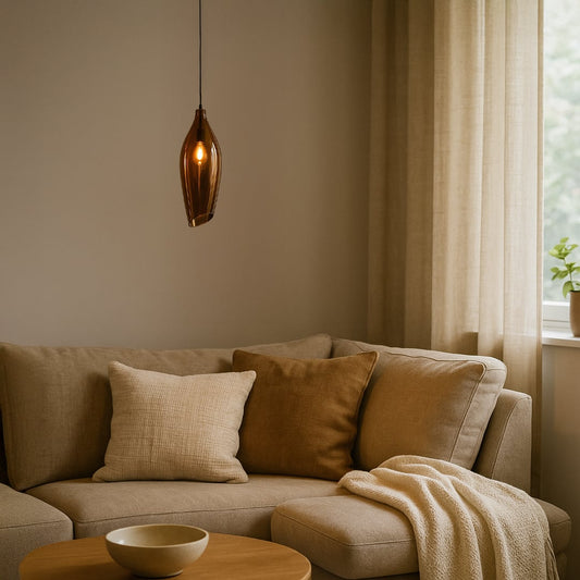 A modern bronze tinted glass pendant light glowing softly above a beige sofa creating warm ambient lighting ideal for living rooms reading corners and cozy interiors.