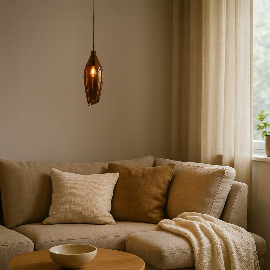 A modern bronze tinted glass pendant light glowing softly above a beige sofa creating warm ambient lighting ideal for living rooms reading corners and cozy interiors.