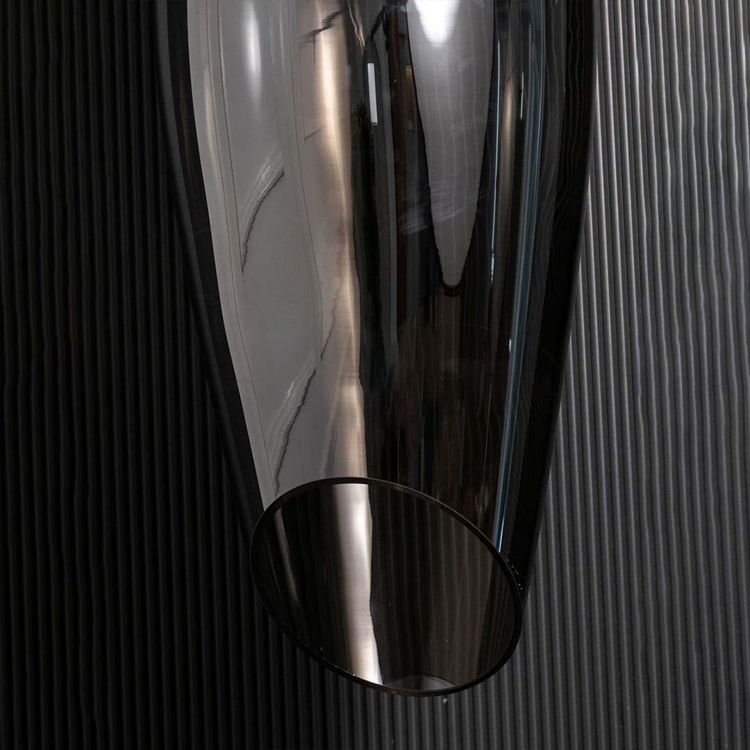 A closeup view of the smoked black pendant light showing the smooth curved glass surface and warm reflective glow ideal for premium interiors.