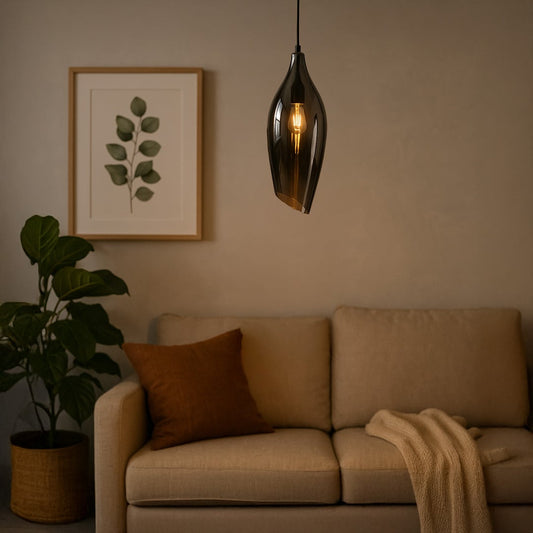 A modern black smoked glass pendant light glowing softly above a beige sofa creating warm ambient lighting ideal for living rooms bedrooms and cozy interiors.