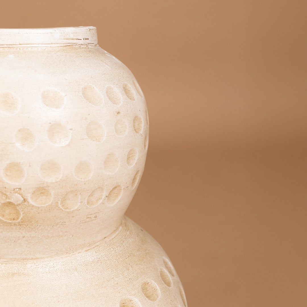 Closeup of cream textured decorative vase with polka dot detailing showing handcrafted finish ideal for stylish modern artistic home decor.