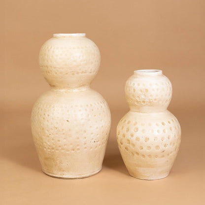 Cream polka dot textured decorative vase displayed with matching decor pieces creating a stylish grouped arrangement for modern interiors.