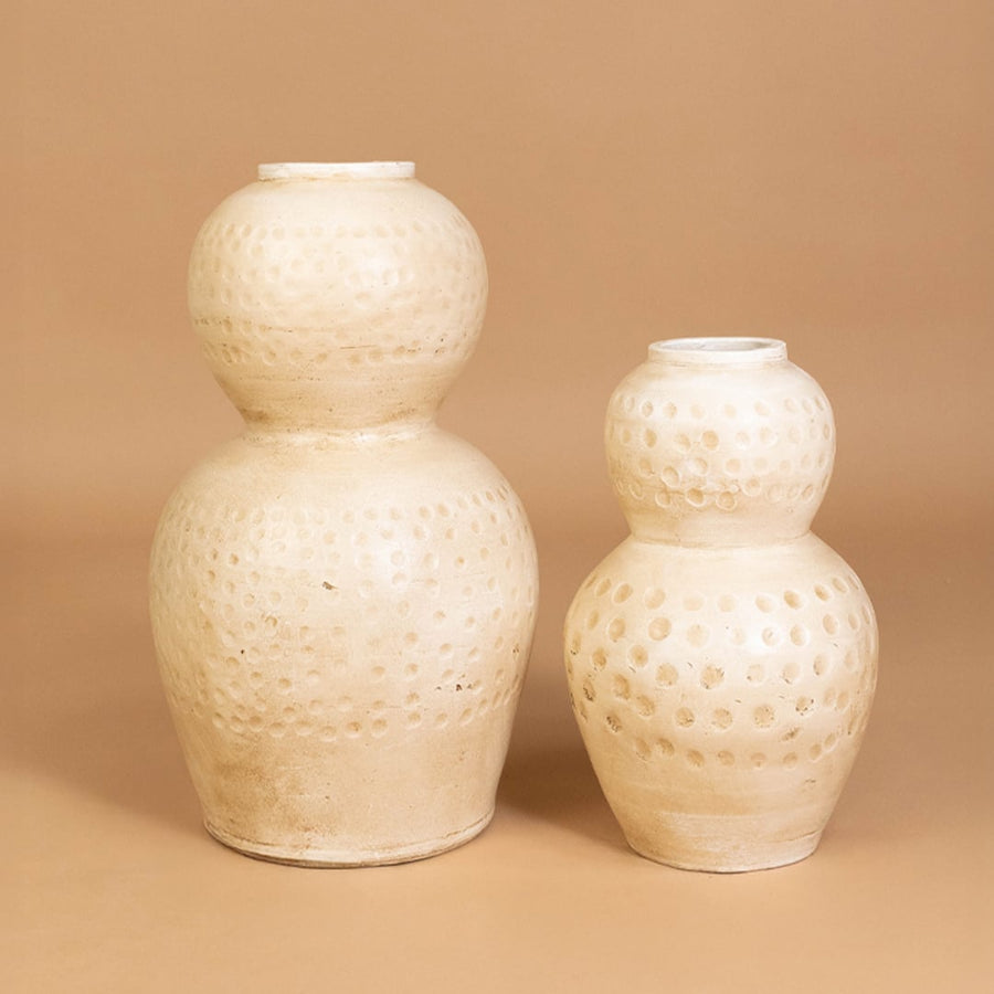Cream polka dot textured decorative vase displayed with matching decor pieces creating a stylish grouped arrangement for modern interiors.