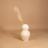 Cream textured decorative vase with polka dot design placed in a styled interior adding warm artistic decor to shelves consoles and living spaces.