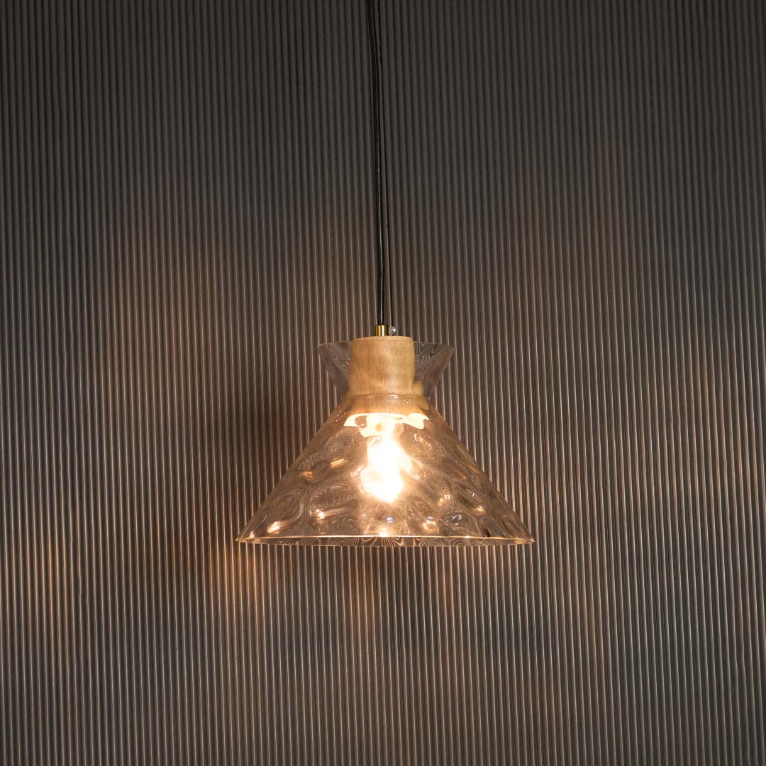 Clear glass pendant light with wooden holder glowing warmly against black background for premium home lighting.