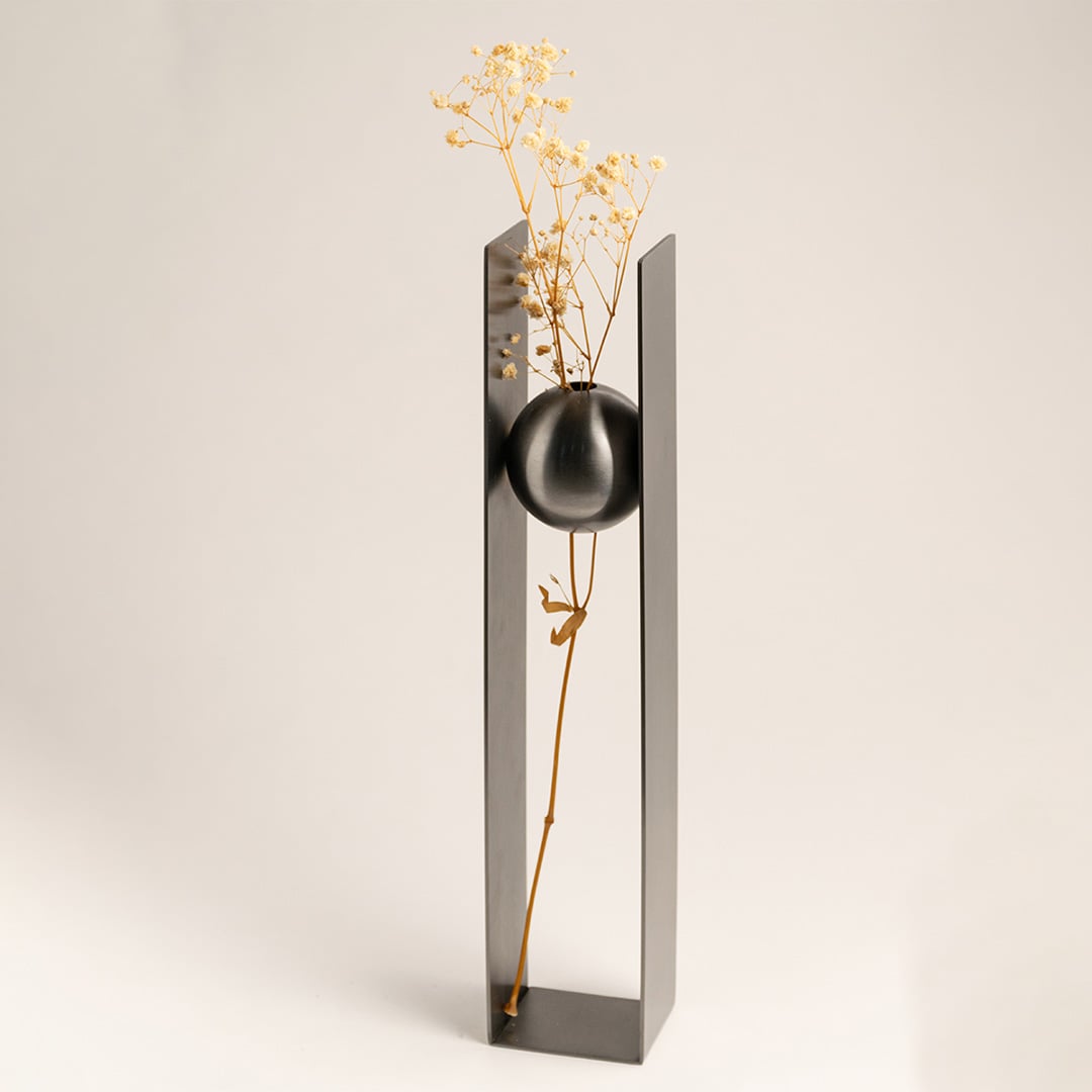 Black metal sphere vase placed on a wooden console with minimal floral arrangement adding a sleek touch to luxury home interiors.