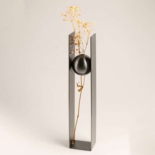 Black metal sphere vase placed on a wooden console with minimal floral arrangement adding a sleek touch to luxury home interiors.
