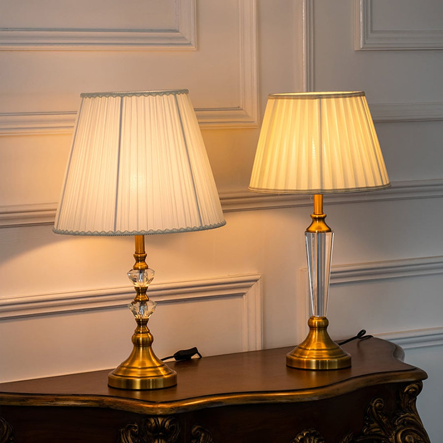 Crystal table lamps turned on grouped together with pleated white shades and gold bases perfect for luxury home lighting and decoration.