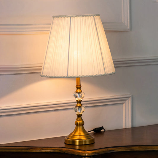Clear crystal table lamp with pleated fabric shade creating elegant classic ambient lighting for luxury interior spaces.