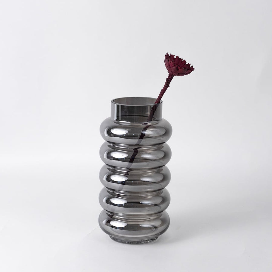 Modern smoky glass vase with single maroon flower styled on a bathroom counter with mirror for elegant minimalist decor.