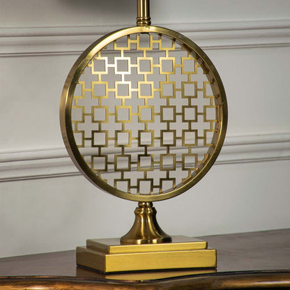 Gold round patterned table lamp shown in close up view on wooden console table with light off for artistic decorative décor.