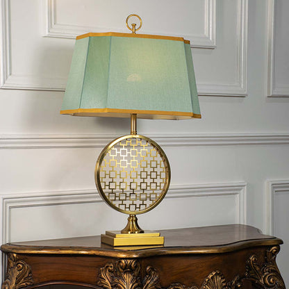 Green shade gold and white patterned table lamp on carved console table with light off for artistic decorative décor.