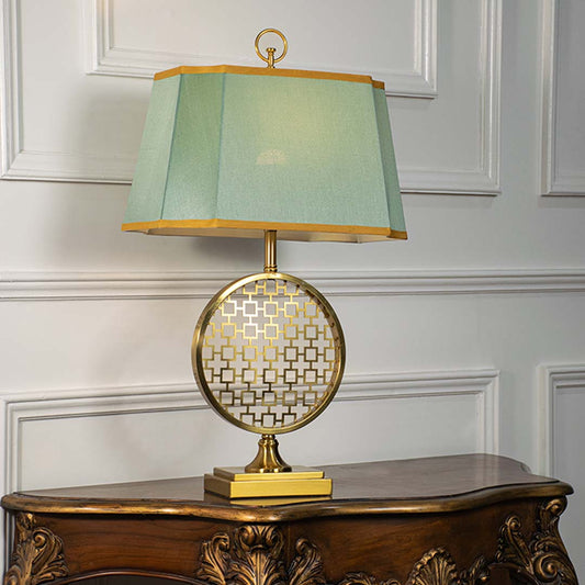 Green shade gold and white patterned table lamp on carved console table with light off for artistic decorative décor.