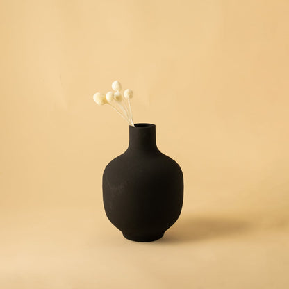 Black textured metal vase styled in a warm minimal scene adding bold modern elegance to contemporary home decor.