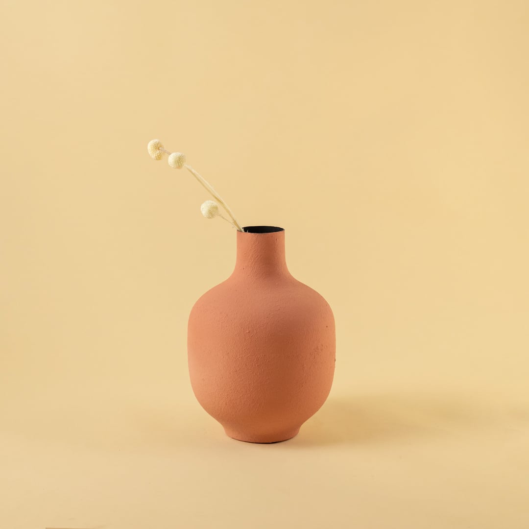 Terracotta textured metal vase styled in a warm neutral scene adding earthy modern charm to contemporary home decor.