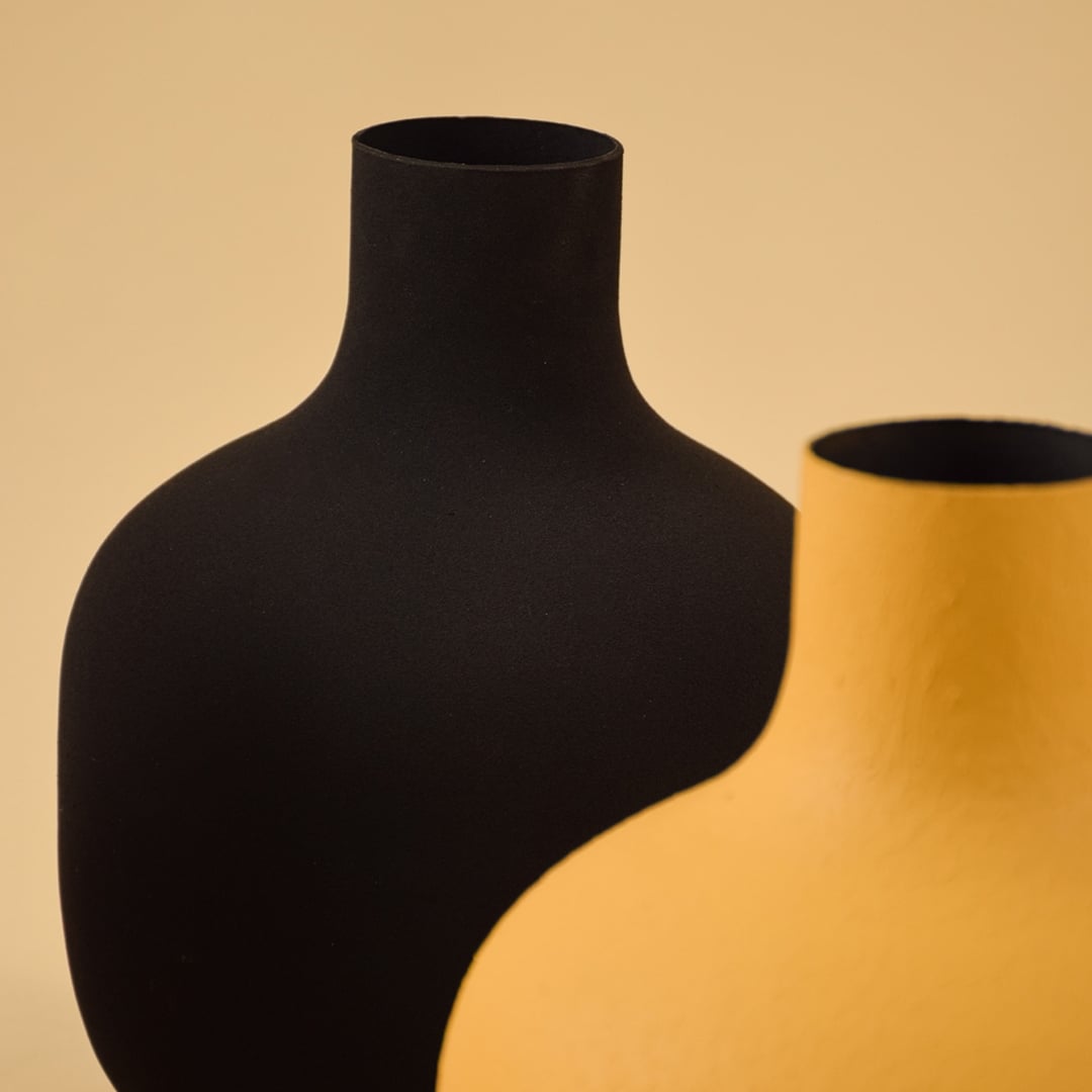 Closeup of black metal vase showing matte textured finish and sculptural shape for a bold modern decor accent.