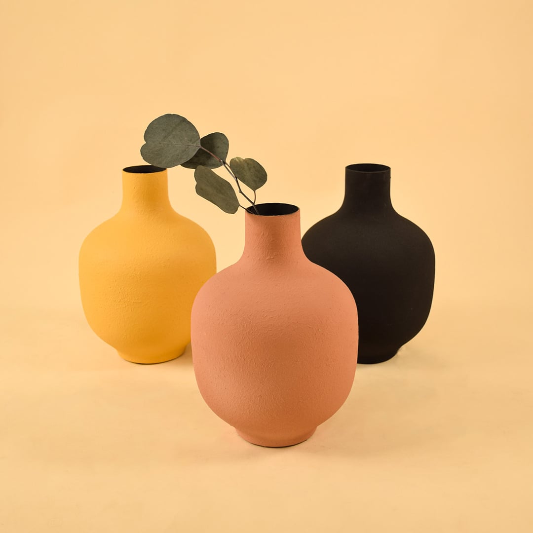 Terracotta textured metal vase grouped with decor pieces creating a warm cohesive look for living and dining spaces.