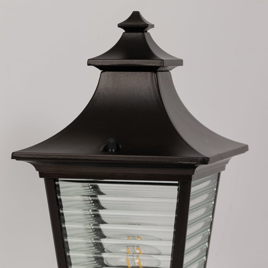 Closeup view of black metal pillar light with ribbed glass body highlighting its detailing for outdoor home lighting.