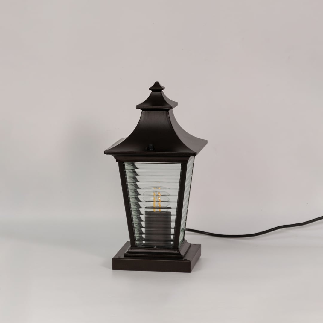 Black metal pillar lamp with ribbed glass panels shown switched off on a white background for outdoor decor.