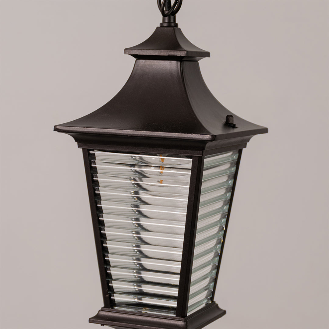 Closeup outdoor wall lantern in black metal with ribbed glass panels for entrance or facade decor lighting white background.