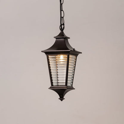 Black metal outdoor hanging lantern with ribbed glass illuminated on white background for modern exterior lighting.