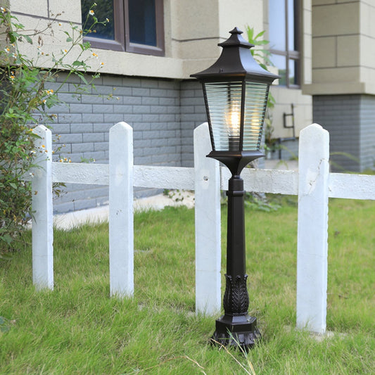 Elegant black outdoor pillar lamp with glass panels lighting a modern entrance area for stylish home exterior decor.