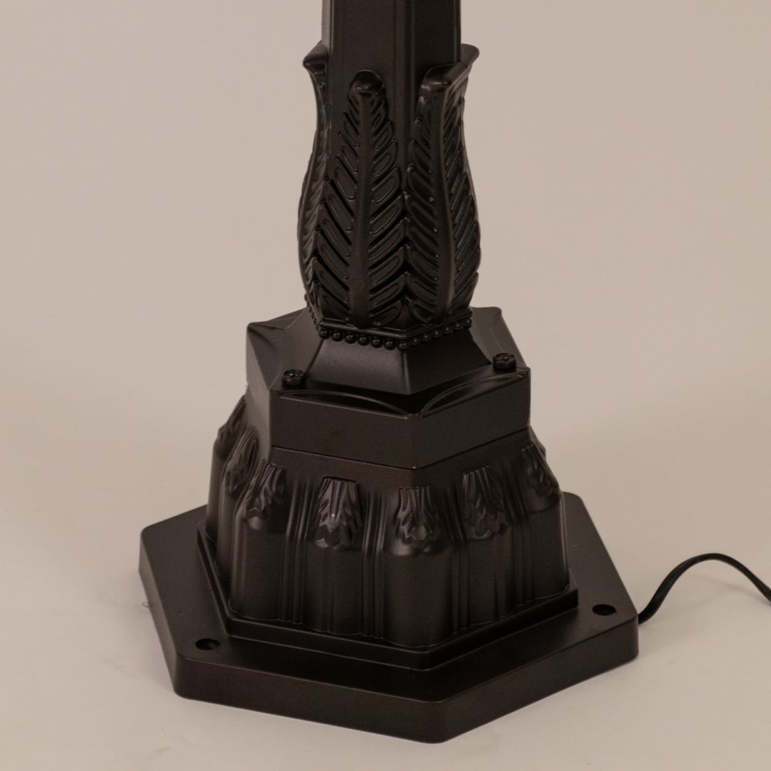 Detailed view of black pillar lamp top section with ribbed glass and warm filament bulb for outdoor home decor.