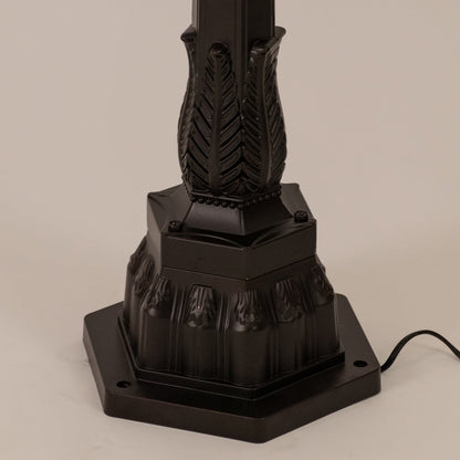 Detailed view of black pillar lamp top section with ribbed glass and warm filament bulb for outdoor home decor.