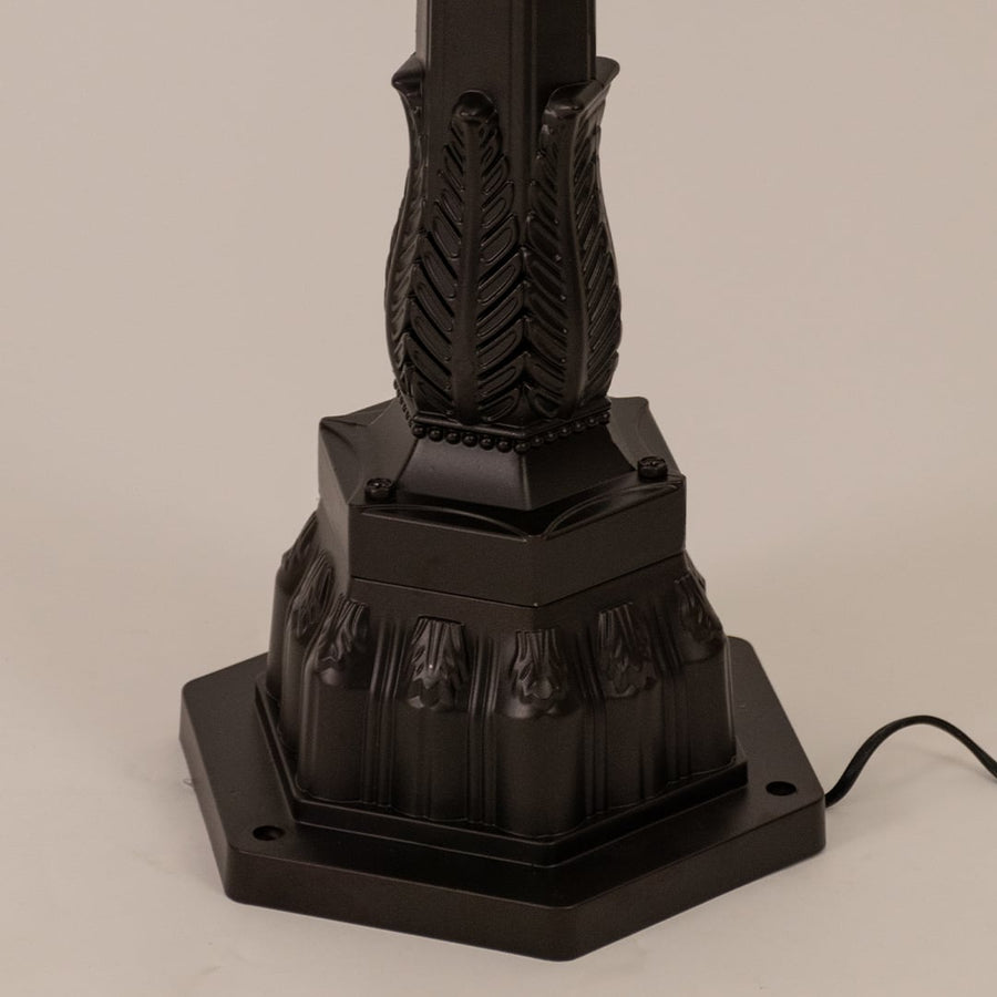 Detailed view of black pillar lamp top section with ribbed glass and warm filament bulb for outdoor home decor.