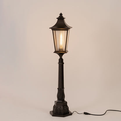 Vintage black outdoor garden light with warm glowing ribbed panels for elegant exterior decor use.