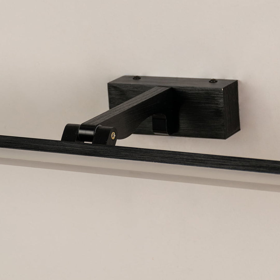 Closeup of black metal picture light showing slim bar design smooth finish and warm directional illumination.