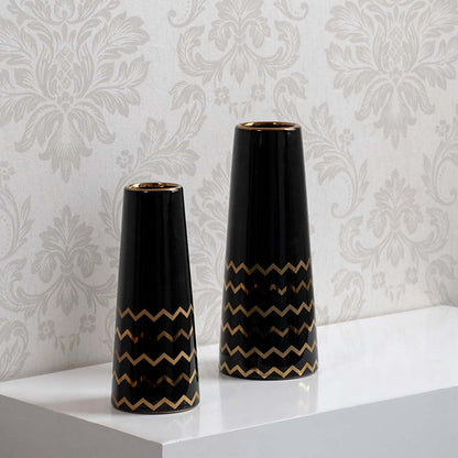A decorative black vase with gold zigzag design displayed in a curated setup showcasing its modern glossy finish and elegant contemporary look.