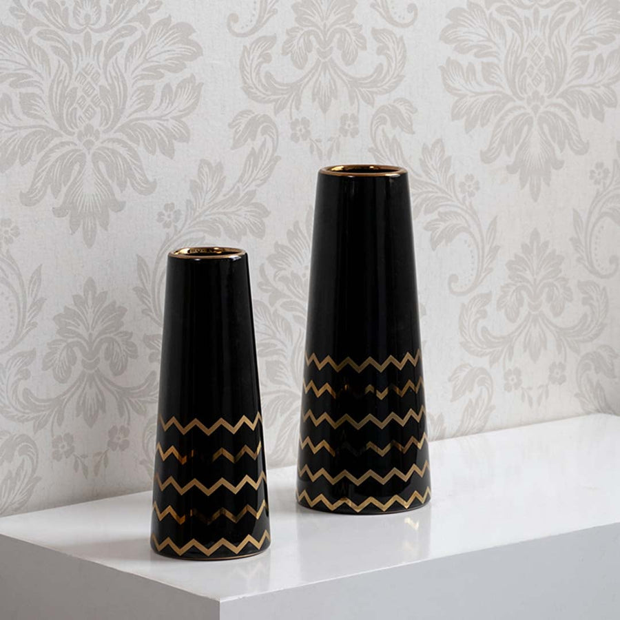 A decorative black vase with gold zigzag design displayed in a curated setup showcasing its modern glossy finish and elegant contemporary look.