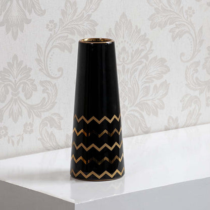 A sleek black ceramic vase with gold zigzag detailing shown on a bright background highlighting its glossy finish and modern artistic style.