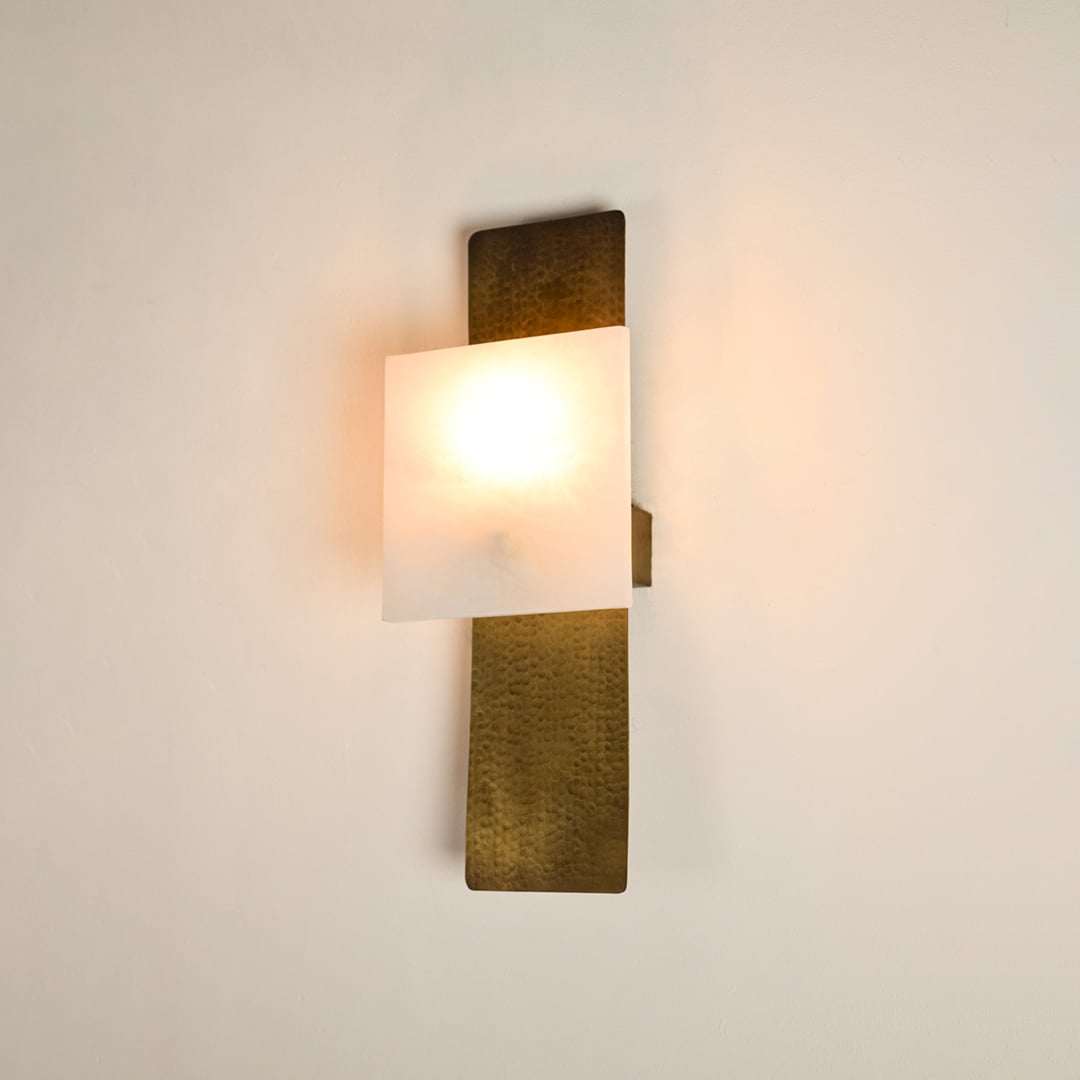 Contemporary marble wall sconce with brass base illuminated on white background featuring artistic rectangular shape ideal for stylish interiors.