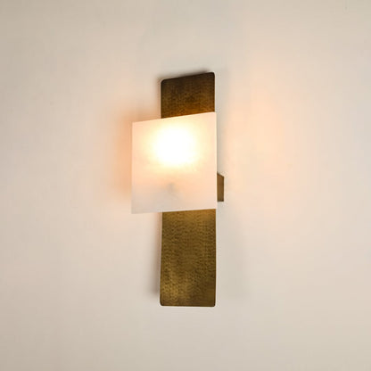 Contemporary marble wall sconce with brass base illuminated on white background featuring artistic rectangular shape ideal for stylish interiors.