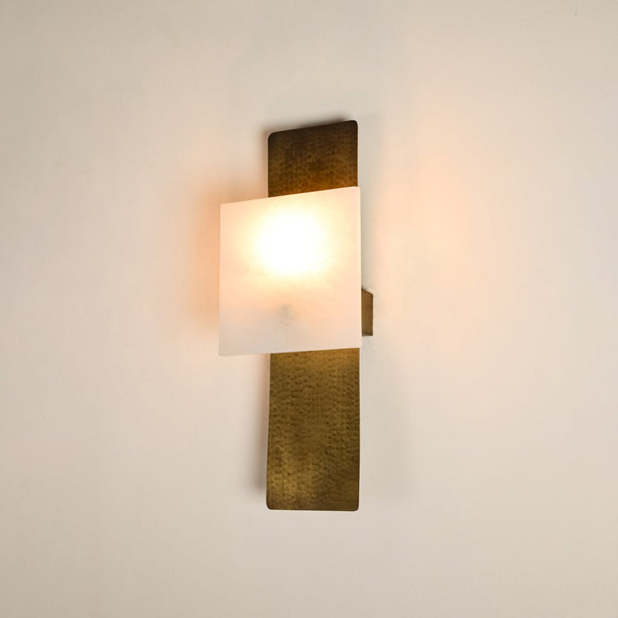 Contemporary marble wall sconce with brass base illuminated on white background featuring artistic rectangular shape ideal for stylish interiors.