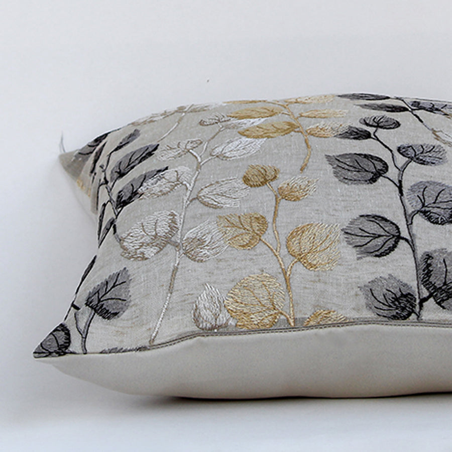 Closeup of cotton cushion embroidery showing intricate gold grey and black leaf stitching and soft textured fabric ideal for stylish home decor accents.