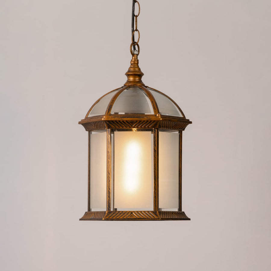 Decorative hanging lantern light turned on against a white background with a warm glow highlighting its antique frame and frosted glass panels.