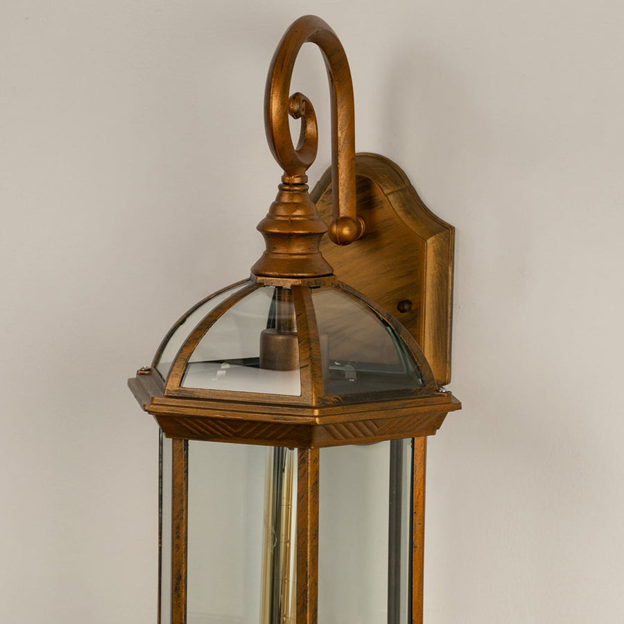 Closeup view of antique gold outdoor wall lantern showing its clear glass panes curved metal top and detailed finish for premium outdoor decor styling.