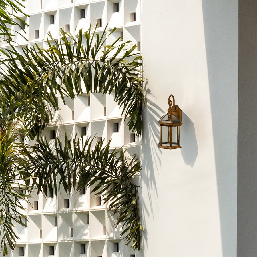 Antique gold outdoor wall lantern with clear glass housing mounted on a bright exterior wall adding elegant illumination and enhancing modern outdoor decor styling.
