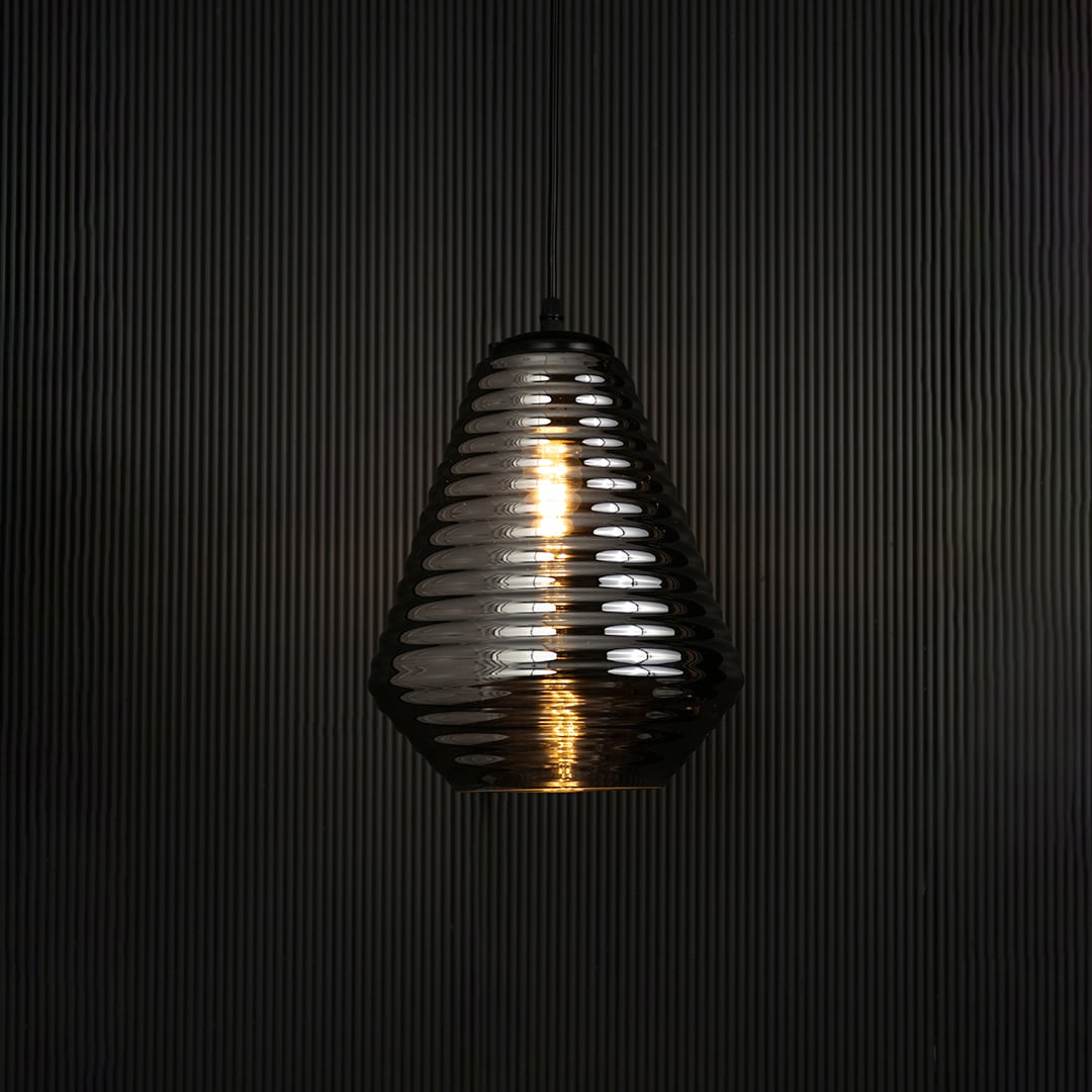 Elegant smoked glass pendant light illuminated on dark background highlighting artistic ribbed texture and refined design appeal.