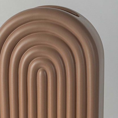 Closeup image of a matte taupe brown ceramic vase featuring a prominent concentric ribbed rainbow arch pattern and slot.