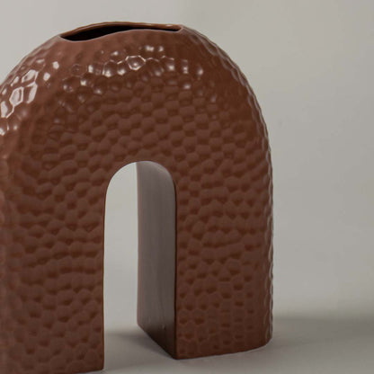 Closeup view of the brown arched ceramic vase highlighting its textured surface and sculptural modern design.