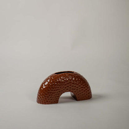 Modern low crescent arch shaped ceramic vase with a brown dotted texture on white background for contemporary styling.