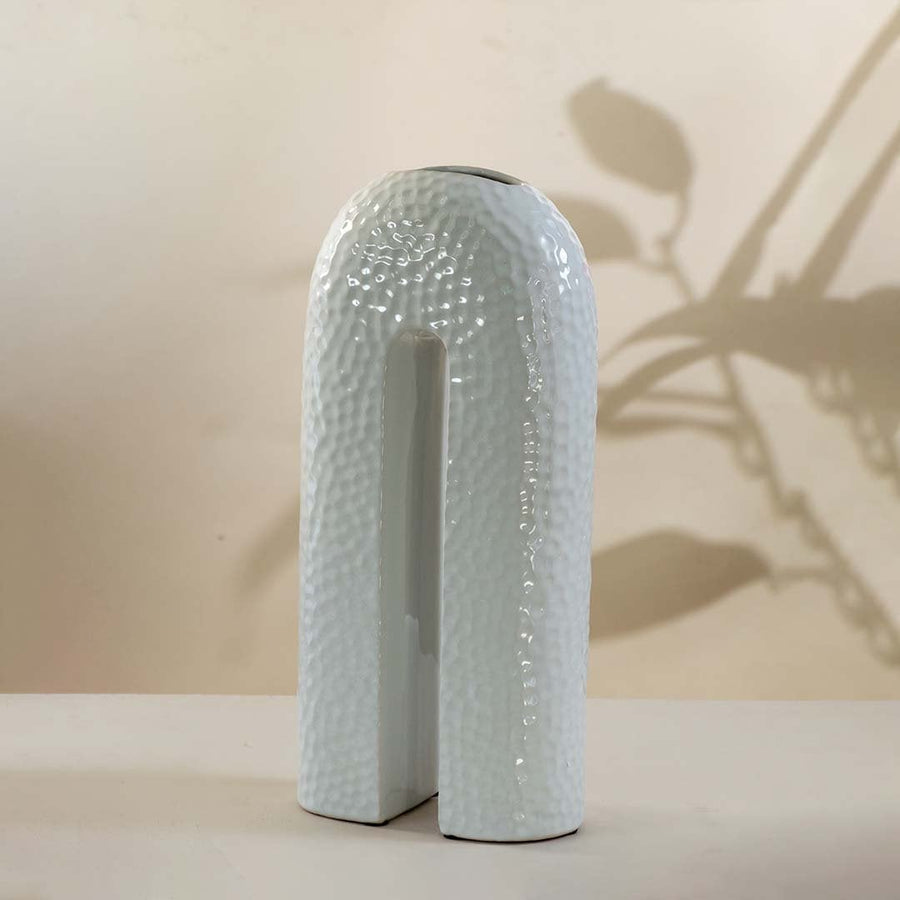 Modern white ceramic arch vase with glossy texture and hollow center shown on white background for home interiors.